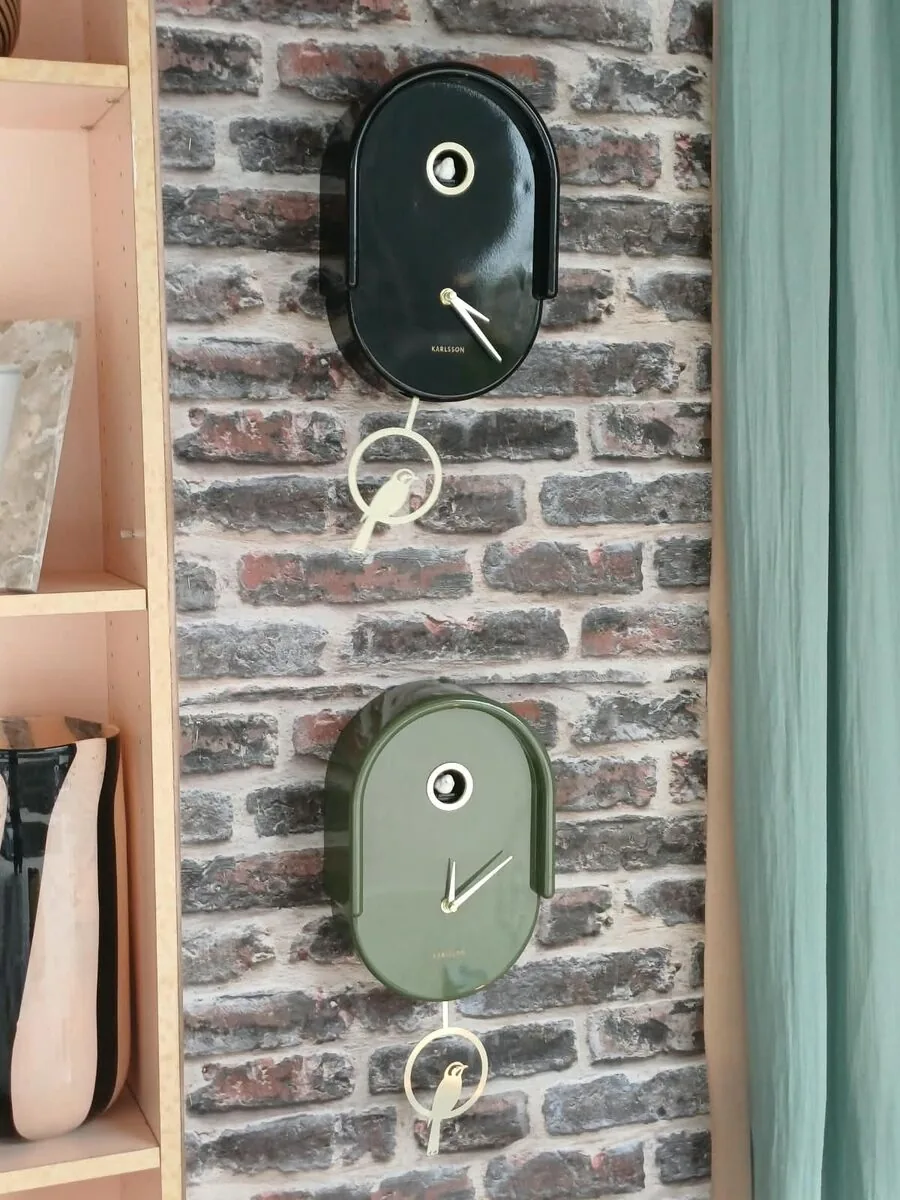 Deux horloges Tweet, noire et verte, sur le mur de briques