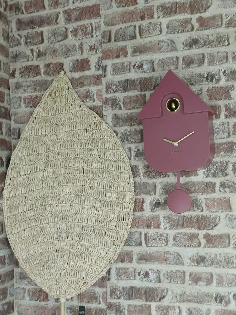 Une horloge coucou près d'une grande feuille tressée