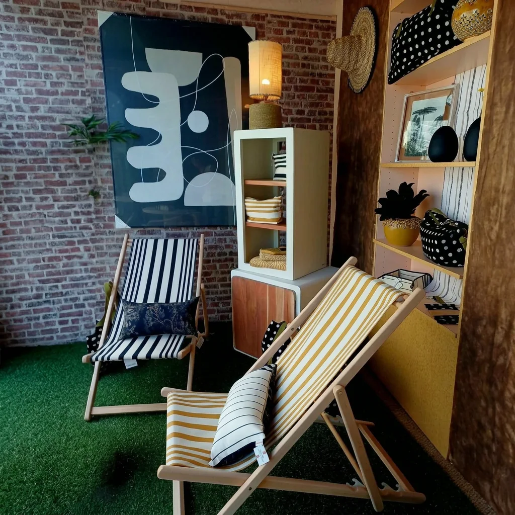 Le coin terrasse de la boutique, transats rayés, étagère de décoration et lampe allumée