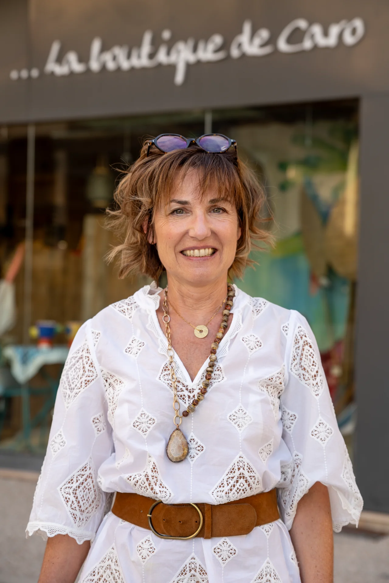 Portrait de Caroline Guinet devant la vitrine de La boutique de Caro, place de l'Église à Saint-Martin-en-Haut